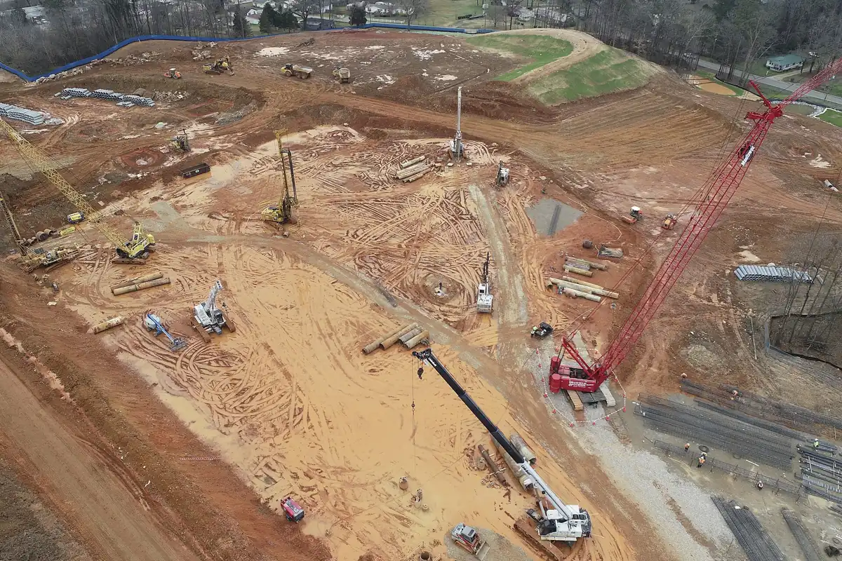 Drone view of early construction sitework with cranes and pile rigs
